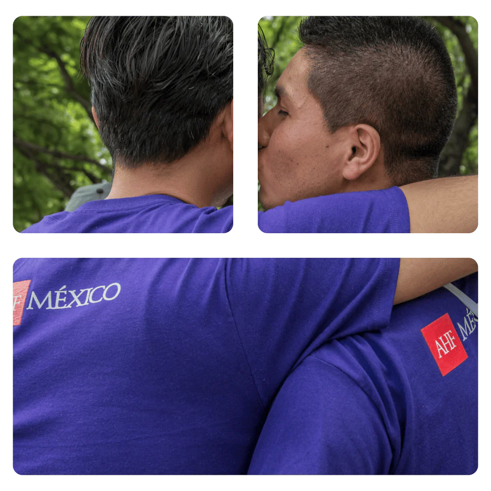 Dos hombres abrazados al aire libre, uno visto de espaldas y otro de perfil, en un entorno con árboles.